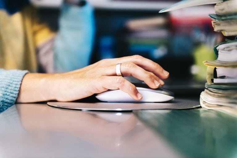 closeup of a female hand clicking computer mouse, technology and teleworking concept, selective focus